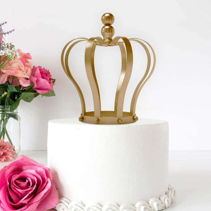 Gold crown cake topper on a white frosted cake with pink flowers.