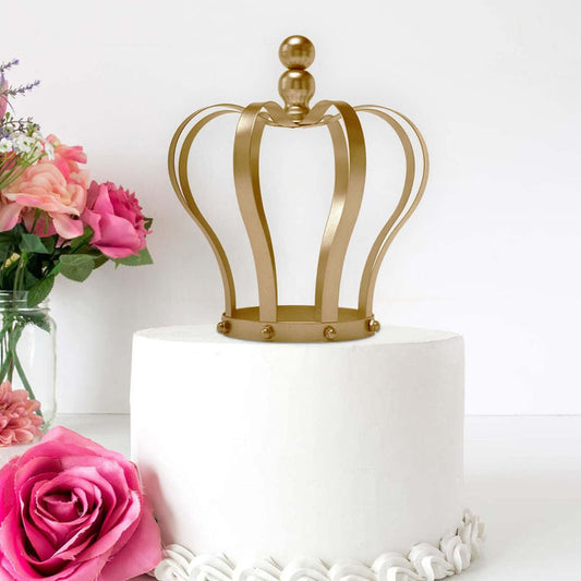 Gold crown cake topper on a white frosted cake with pink flowers.