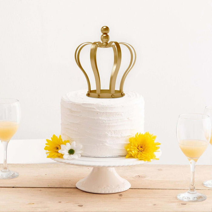 Crown-topped cake with yellow flowers and drinks on a white pedestal.