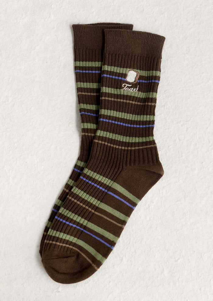A pair of brown socks with green stripe and 'toast' embroidery motif.