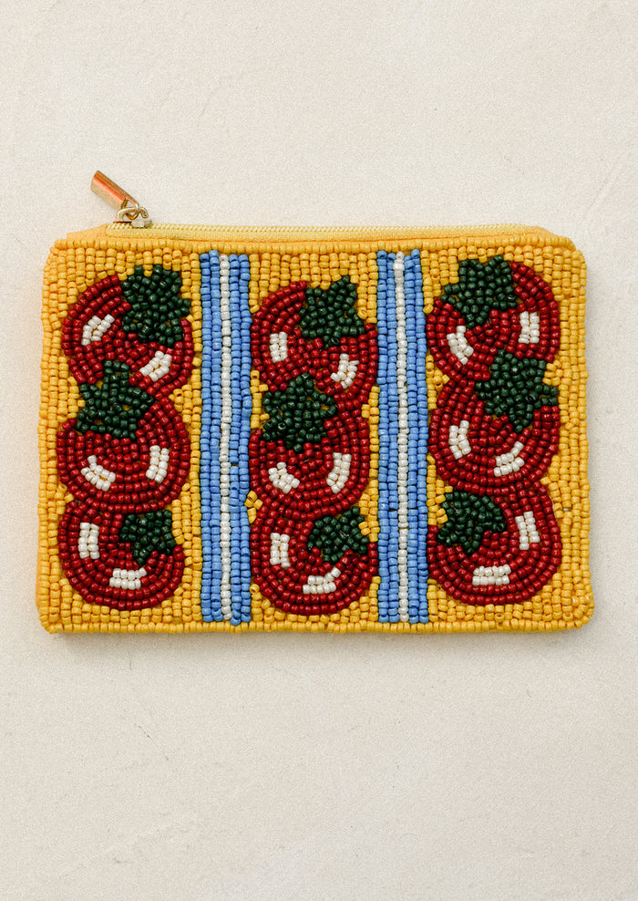 Beaded pouch with red tomato patterns on a yellow background.