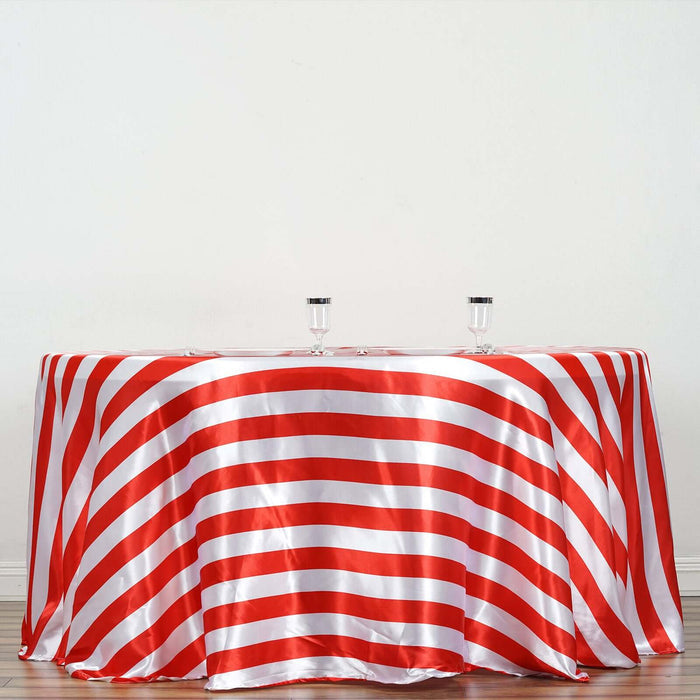 Red and white striped tablecloth draped over a round table with glasses on top.