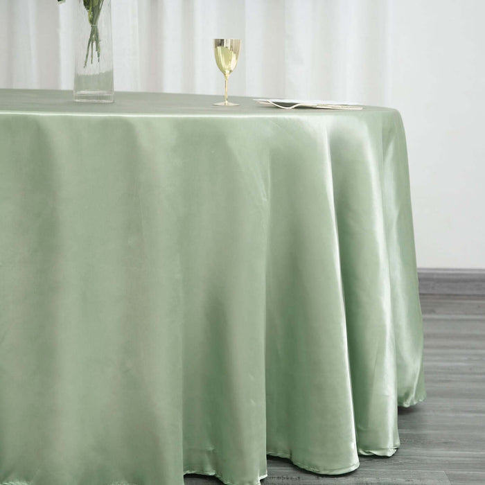 Elegant green satin tablecloth draping over a table with a glass and plate.