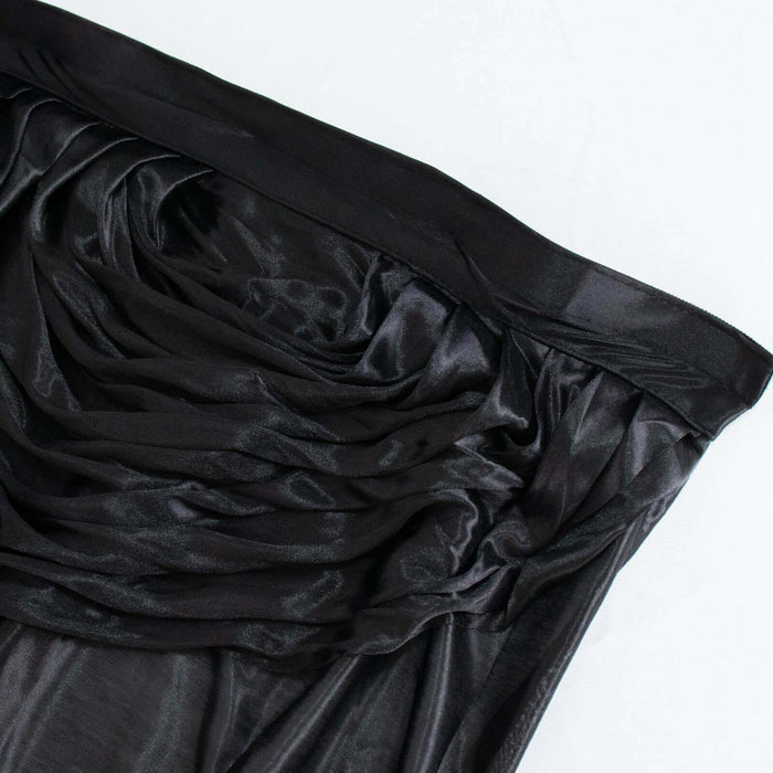 Black draped fabric with a glossy finish on a plain background.