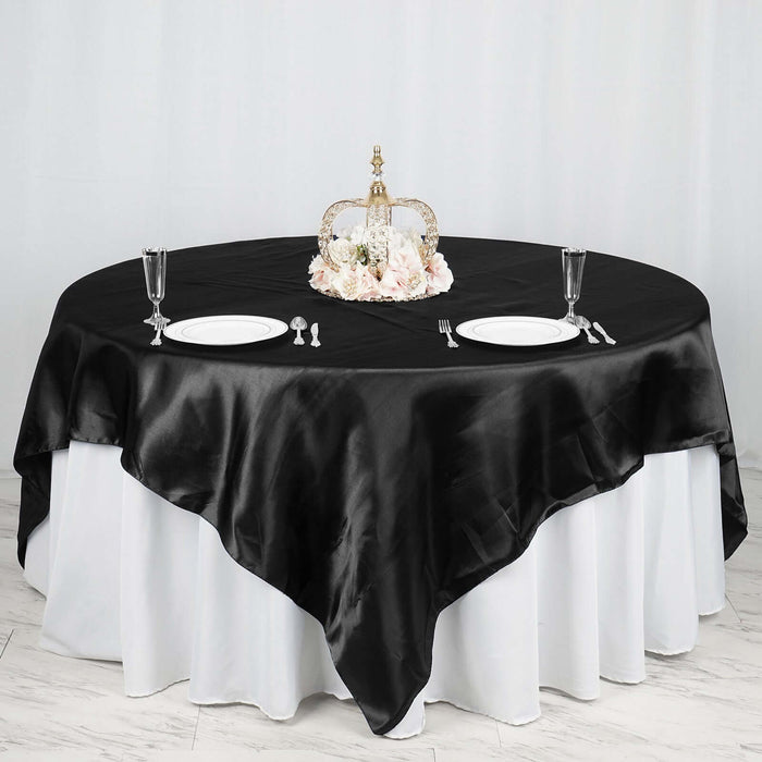 Elegant black satin tablecloth draped over a round table with floral centerpiece.