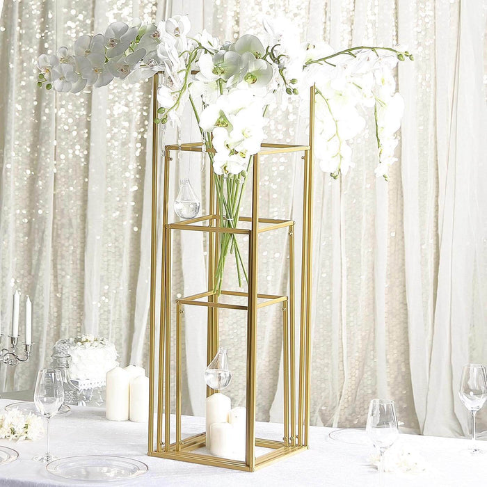 Gold flower vase stand with white orchids and candles on a table.