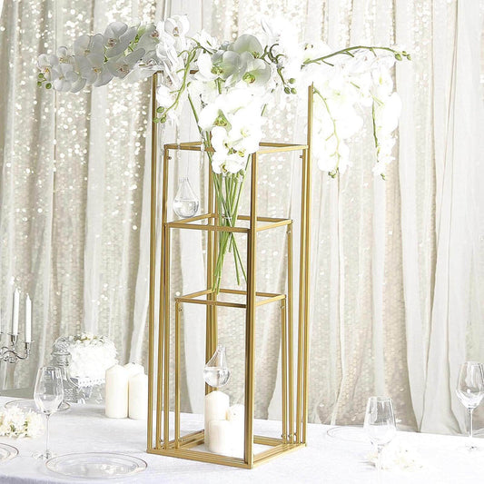 Gold flower vase stand with white orchids and candles on a table.