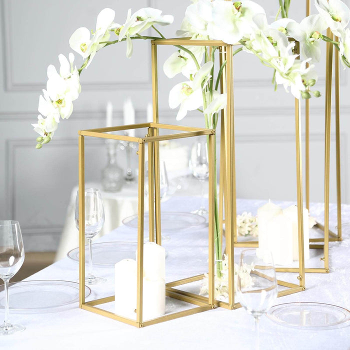 Gold lantern centerpiece with white orchids and candles on a dining table.