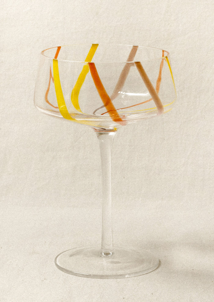 Clear coupe glass with colorful stripes.