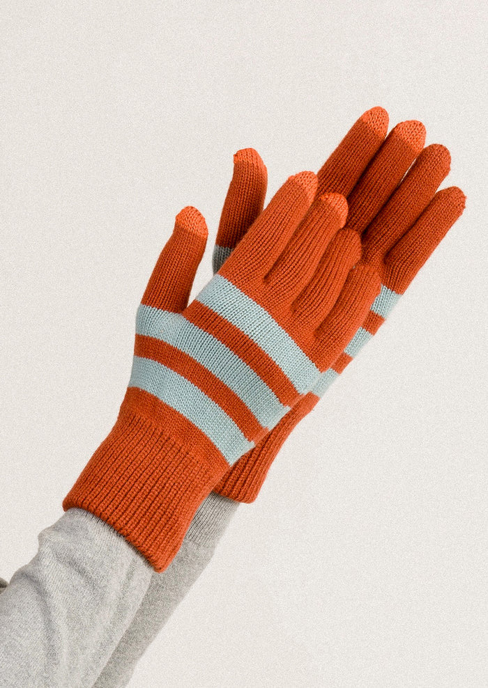 Pair of orange gloves with light blue stripes on a neutral background