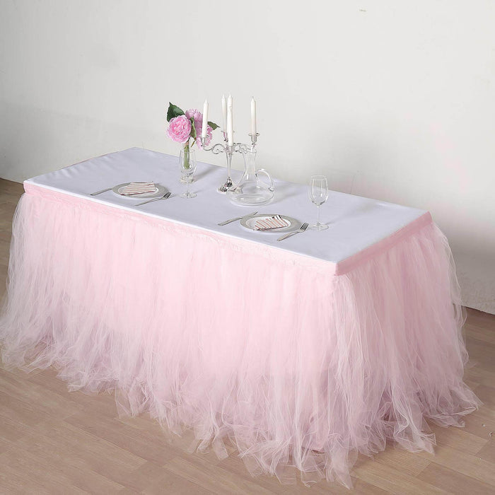 Pink tulle table skirt draped over a white table for elegant decor.