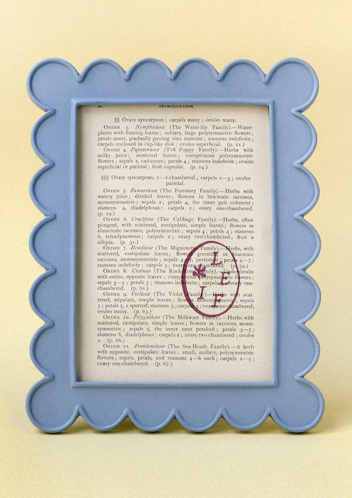 A powder blue 5" x 7" picture frame with a scalloped design.