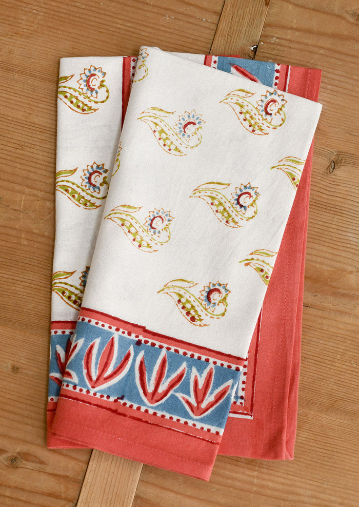 Two decorative napkins with floral patterns on a wooden surface